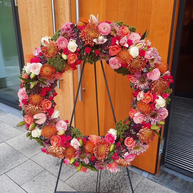 Rouwkrans van bloemen op een standaard, gemaakt door Bloemies
