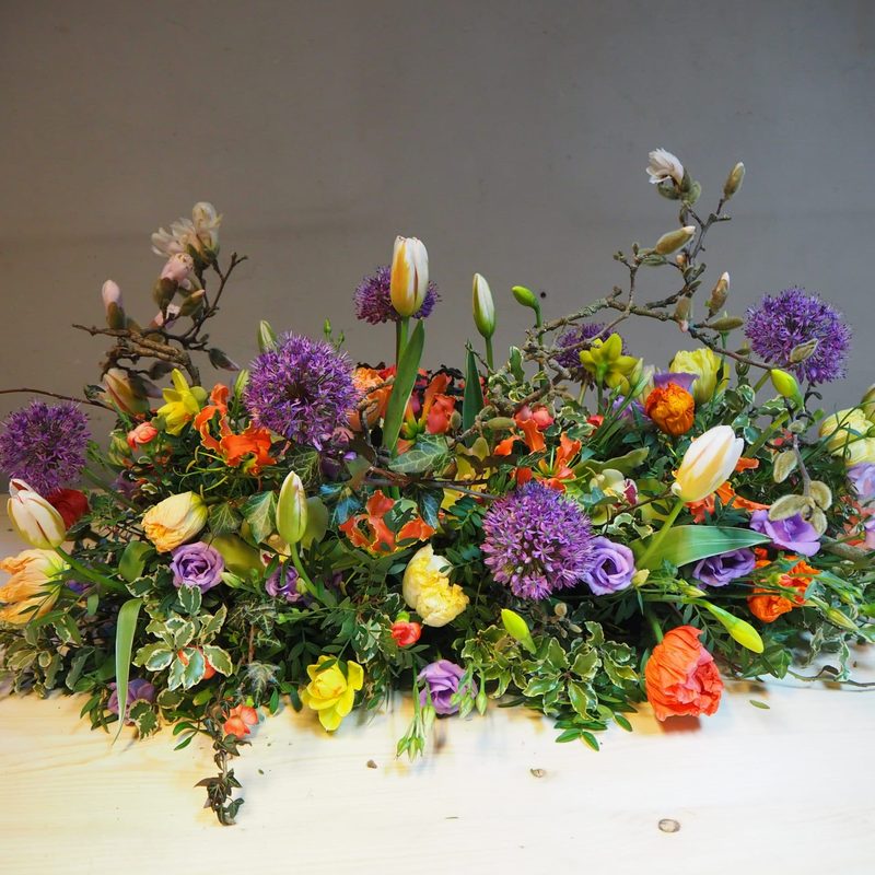 Kleurrijk rouwstuk met losse, natuurlijk gestoken bloemen, gemaakt door Bloemies