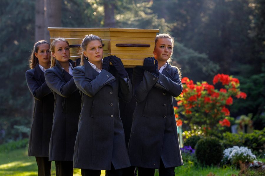 Een team van vrouwelijke dragers draagt een kist op de schouders