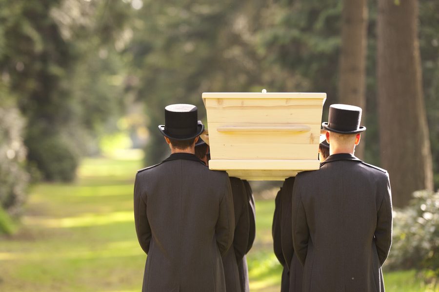 Twee dragers met hoge hoed dragen een kist op de schouder