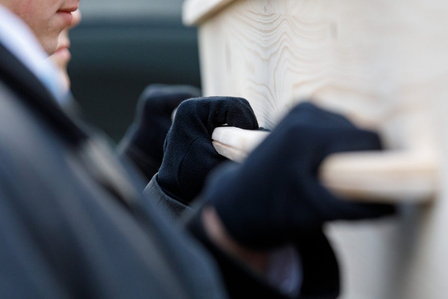 Handen in handschoenen tillen een kist op, detail
