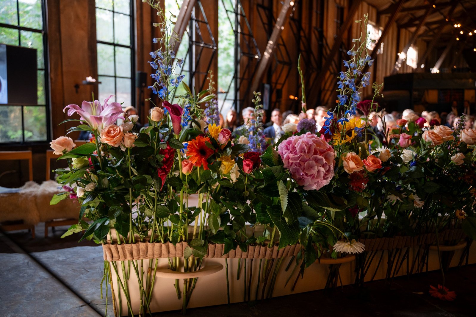 Kist vol losse bloemen tijdens een afscheidsbijeenkomst, met de gasten op de achtergrond