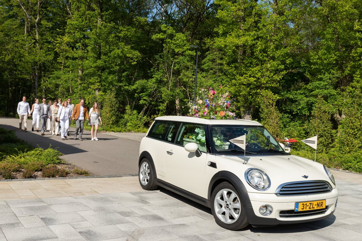 Familie loopt achter de Minirouwauto bij een uitvaart