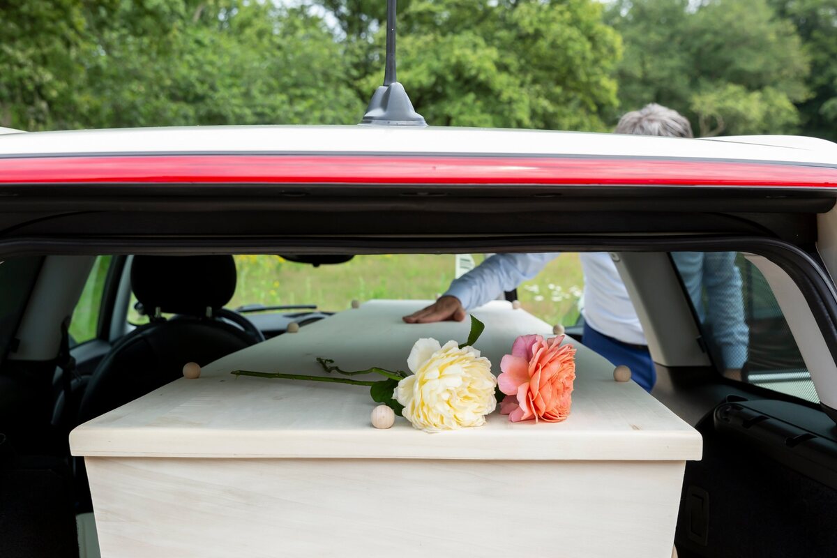 Een lichte houten kist met twee rozen in de Minirouwauto